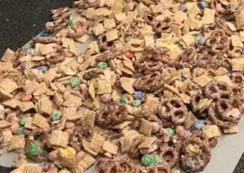 A bowl filled with White Trash snack mix, showcasing its various ingredients like cereal, pretzels, and white chocolate.