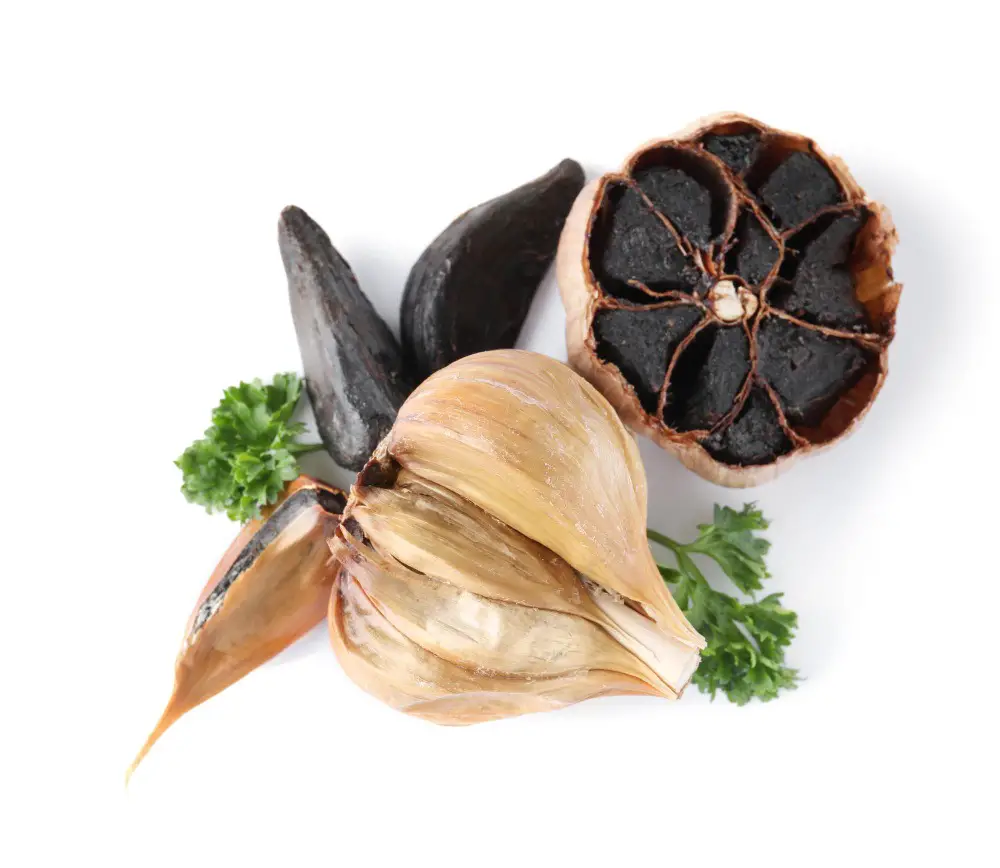A close-up photo of black garlic cloves arranged in a rustic bowl, showcasing its dark color and soft texture.