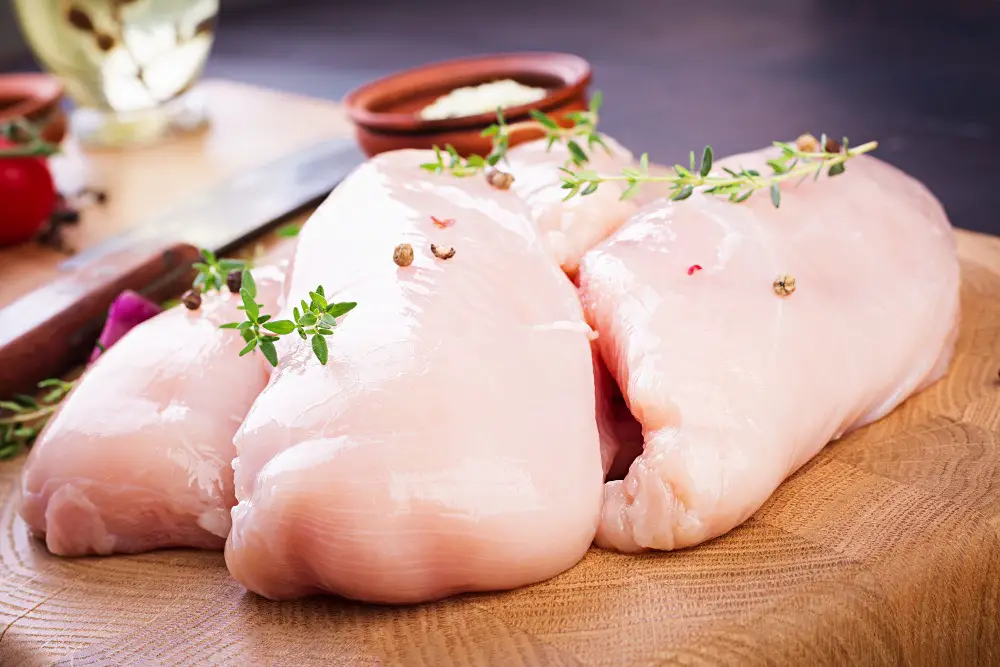 A skilled chef expertly slices a perfectly cooked chicken breast into thin, delicate pieces on a wooden cutting board.