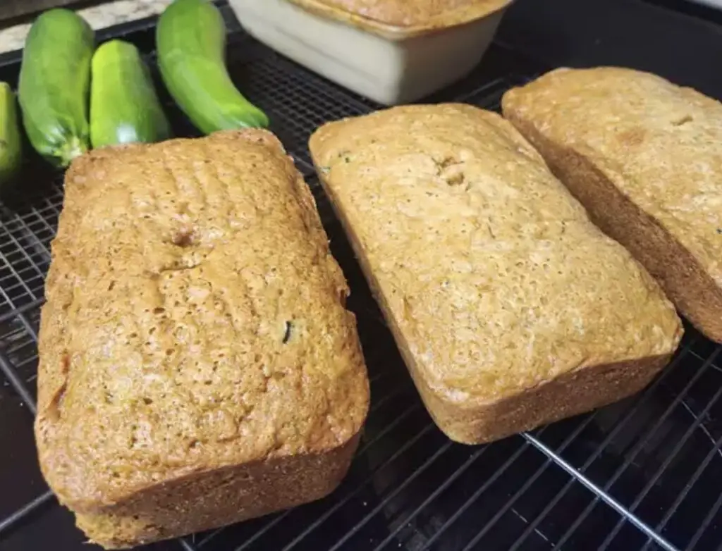 A freshly baked loaf of moist and delicious zucchini bread, with visible shreds of zucchini and a golden crust.
