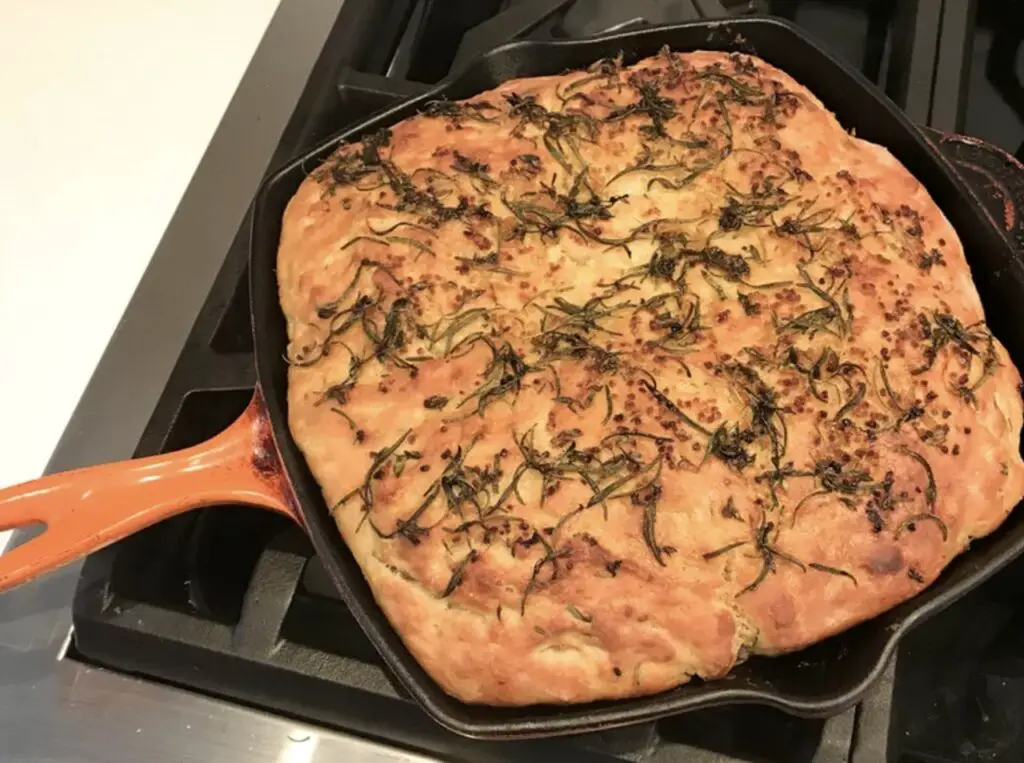 A golden-brown baked focaccia topped with fresh rosemary and sea salt.