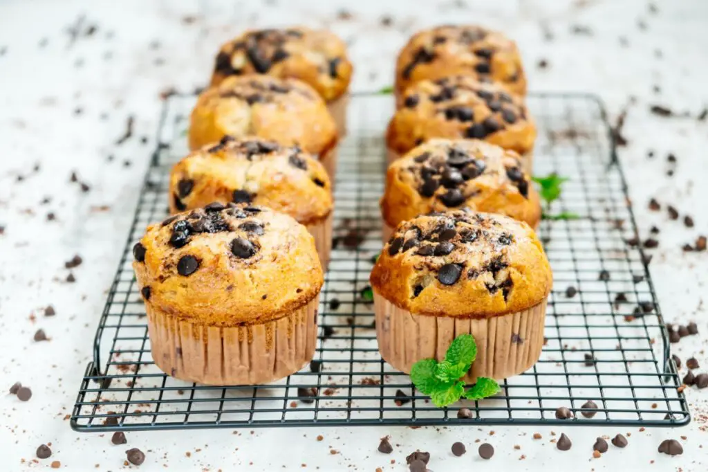 Close-up of a freshly baked zucchini muffin with chocolate chips on a wooden table.