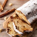 Image of freshly baked Stollen bread, dusted with powdered sugar, surrounded by festive holiday decorations