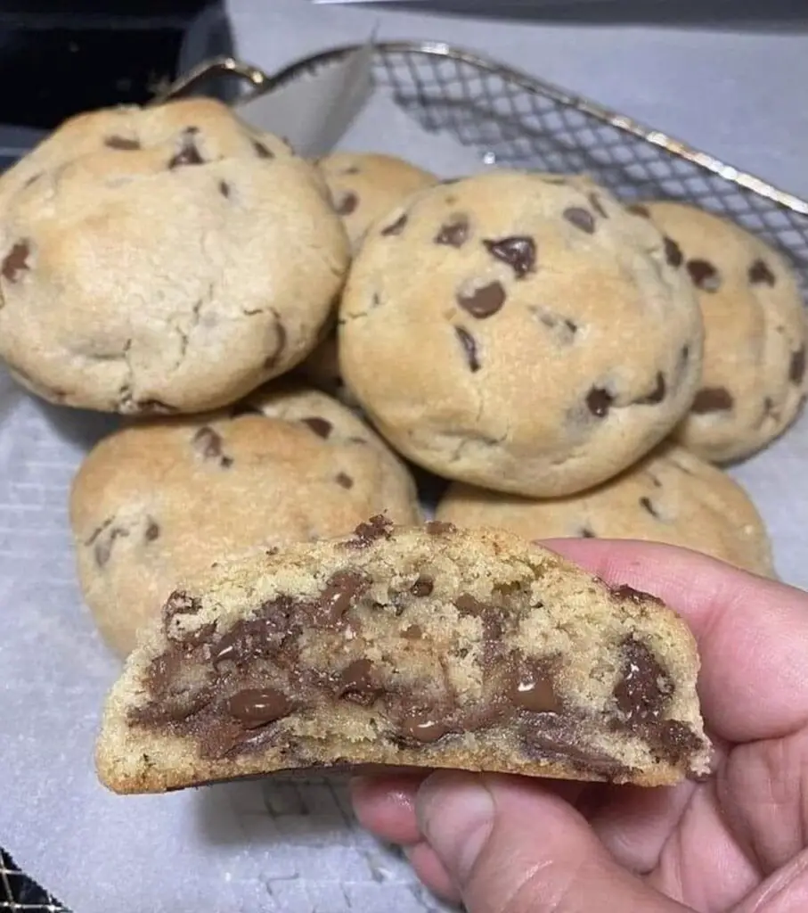 A close-up image of freshly baked chocolate chip cookies, golden brown and oozing with melty chocolate chips. The cookies are arranged on a rustic wooden surface, inviting you to savor their homemade goodness.