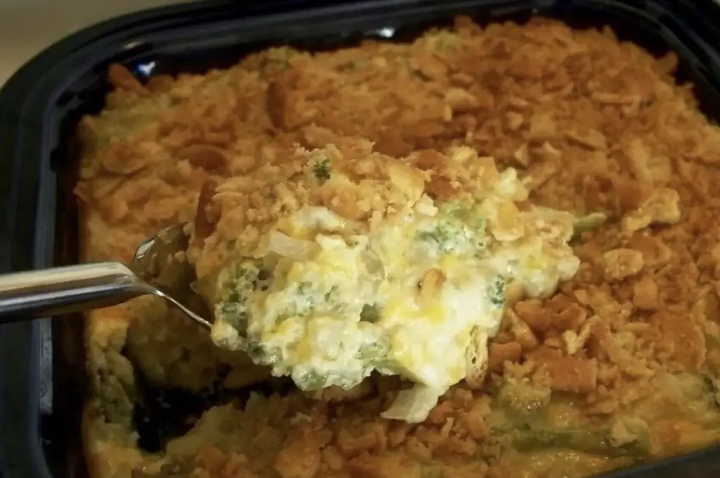 A golden-brown casserole dish filled with Creamy Broccoli Casserole, adorned with a crunchy layer of buttery crackers. Steam rises, revealing the inviting aroma of a comforting dish.