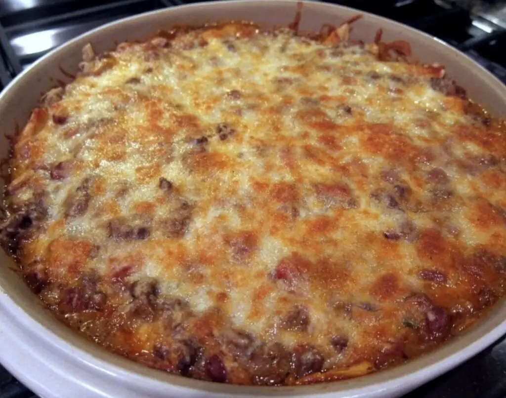 A tempting image showcasing a bubbly and golden Mexican Casserole fresh from the oven, adorned with layers of tortillas, seasoned ground beef, black beans, corn, and melted cheese. A sprinkle of fresh cilantro adds a vibrant touch. Serve with dollops of sour cream and guacamole for a complete feast.