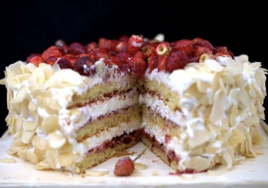 A captivating image showcasing the exquisite layers of White Chocolate Almond Raspberry Cake, adorned with swirls of almond-infused frosting and crowned with fresh raspberries. Each slice promises a harmonious blend of flavors and visual delight.