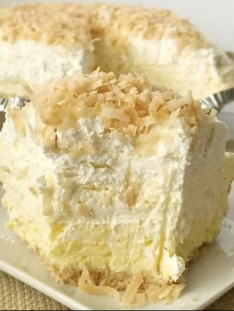 A captivating image showcasing a slice of No-Bake Coconut Cream Pie, with a velvety coconut cream filling, a golden graham cracker crust, and a generous layer of whipped cream. Toasted coconut flakes adorn the top, adding a touch of tropical allure.