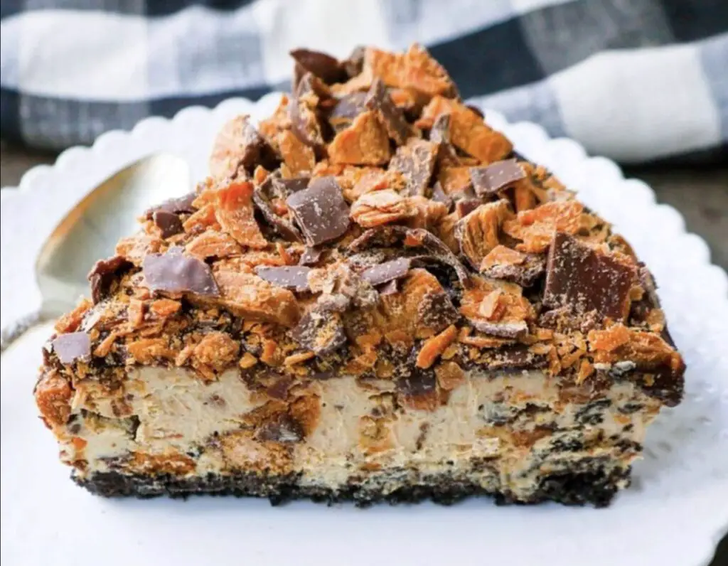 An enticing image featuring a slice of Butterfinger Pie, showcasing the velvety peanut butter filling, chocolate cookie crust, and a generous sprinkle of crushed Butterfinger candy on top. Each slice promises a heavenly blend of creaminess and crunch.