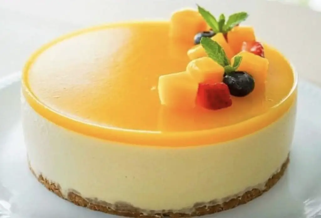 An enticing image featuring a slice of Mango Cheesecake, showcasing the smooth and creamy texture of the cheesecake layer with a vibrant mango swirl. The buttery graham cracker crust adds a perfect contrast to the tropical delight.