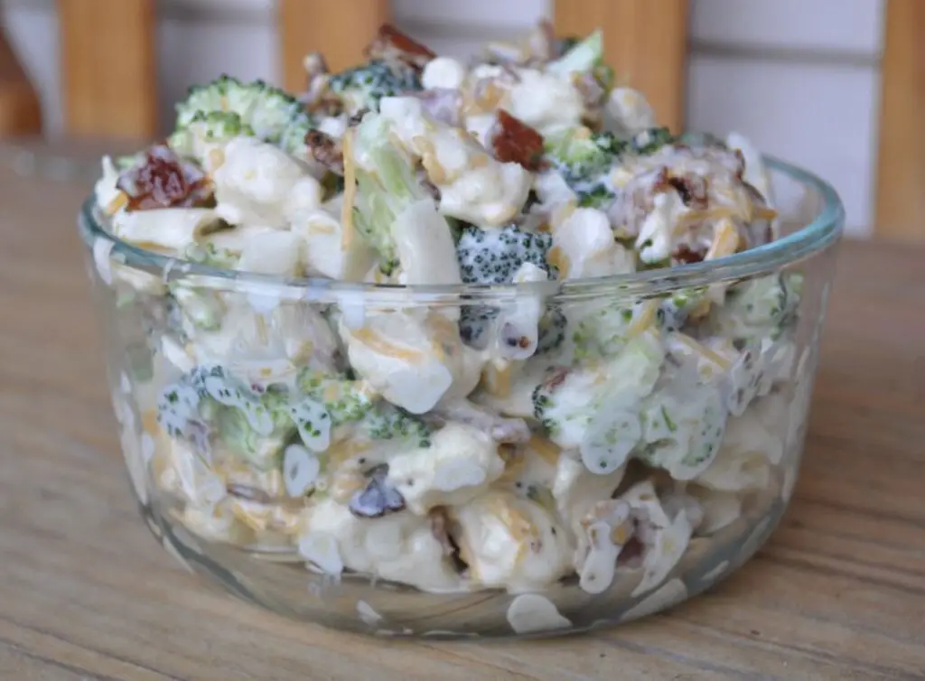 A captivating image featuring Amish Broccoli Salad—a vibrant mix of blanched broccoli, crumbled bacon, red onions, and shredded cheddar cheese, generously coated in a creamy dressing. A visual feast that captures the essence of wholesome flavors.