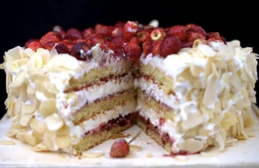 A luxurious image featuring White Chocolate Almond Raspberry Cake, adorned with layers of almond-infused cake, creamy white chocolate frosting, and vibrant raspberries. The cake is a visual and culinary masterpiece, perfect for special occasions.